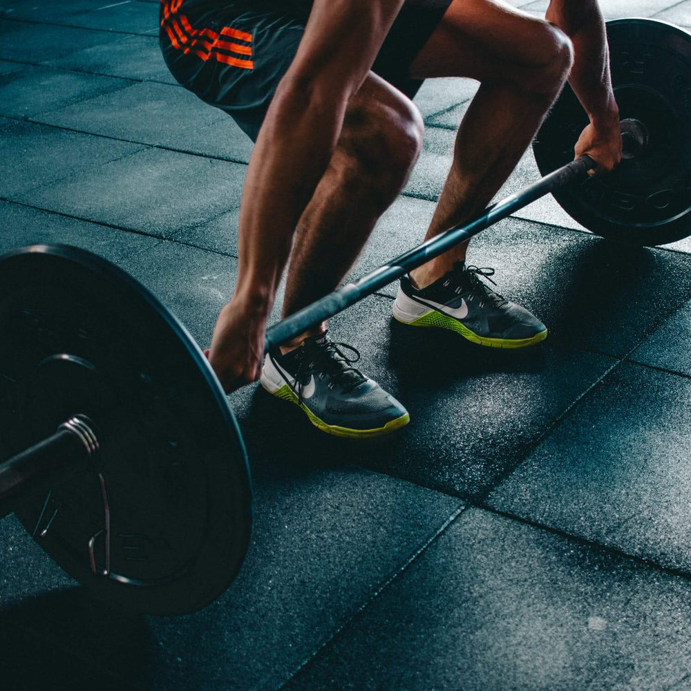 Person lifting a barbell in a gym, focusing on strength training for fitness and muscle development.