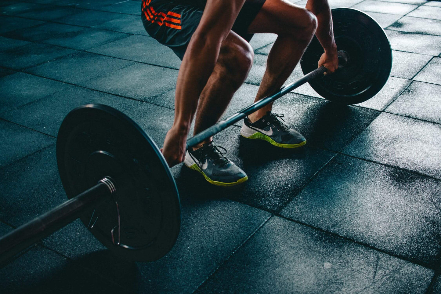 Person lifting a barbell in a gym, focusing on strength training for fitness and muscle development.