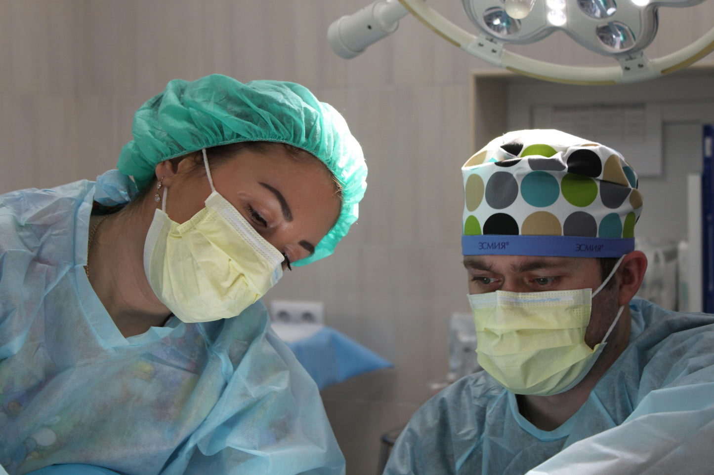 Two surgeons in surgical attire and masks, focused on a procedure in a well-lit operating room.