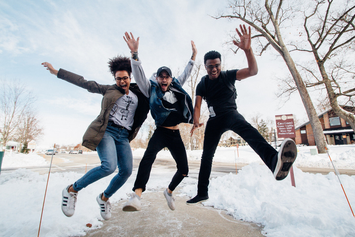 Three friends joyfully jumping in the snow, showcasing excitement and fun during winter.